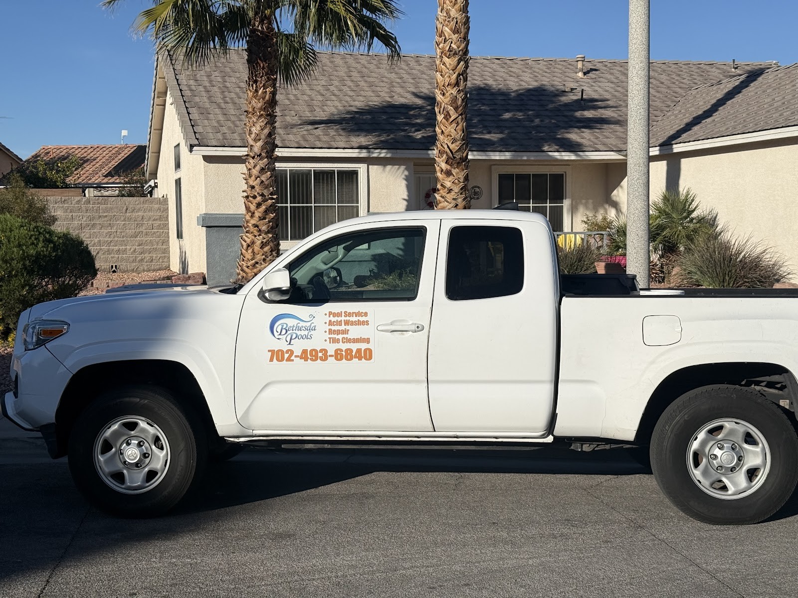 Side view of white Bethesda Pools Toyota Tacoma service truck