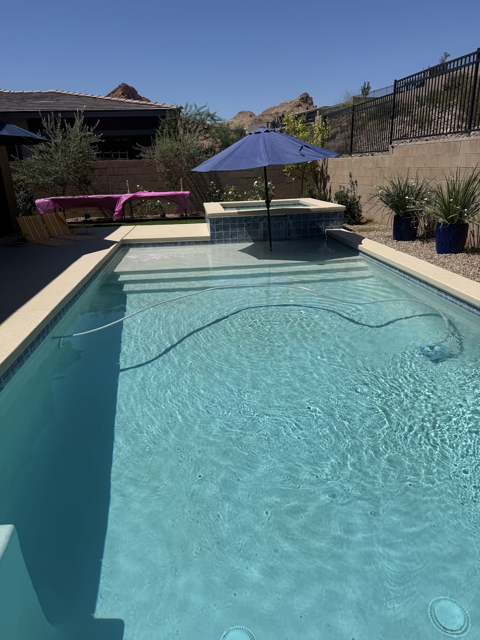 Clean backyard swimming pool with spa and umbrella in a desert setting